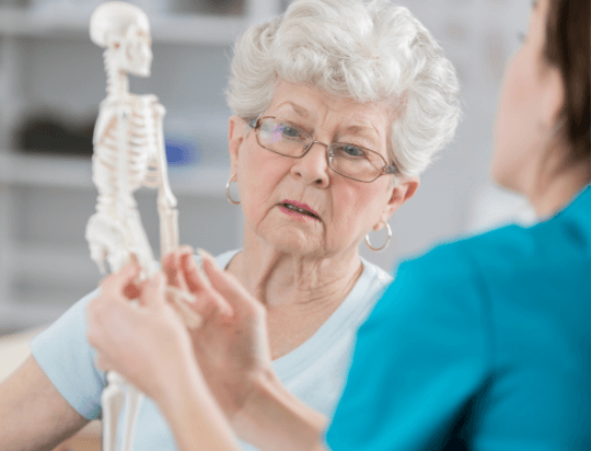 Ostoporosis – Woman looking at skeleton Bone Health Clinic - Osteoporosis treatment near me - OSMC - orthopedics - orthopedic surgery Elkhart IN - orthopedic surgery Goshen IN - orthopedic surgery Middlebury IN - orthopedic surgery Nappanee IN - orthopedic center near me - orthopedic clinic near me - orthopedic doctor
